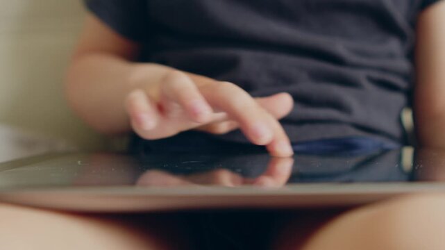 Child using a touch screen tablet for leisure and entertainment.