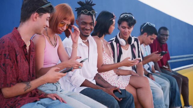 Diverse group of young friends using smartphones together outdoors
