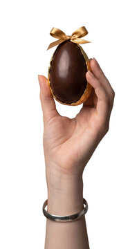 Caucasian woman hand holding a chocolate easter egg with gold ribbon