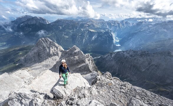 Hiker with helmet at the summit of the Watzmann middle peak, view over mountains, K&ouml;nigssee and Obersee, hiking trail to the Watzmann, Watzmann crossing, Berchtesgaden, Bavaria, Germany