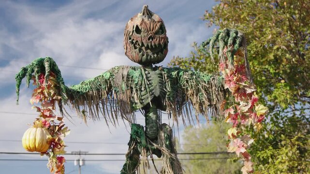 Close-up Halloween scarecrow with pumpkin head and autumn decorations
