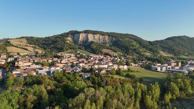 Lugagnano Val d'Arda lies beneath the Monte Giogo badlands, with Pliocene clay ridges, vineyards and wooded slopes in Piacenza, Emilia-Romagna, Italy, drone pullback