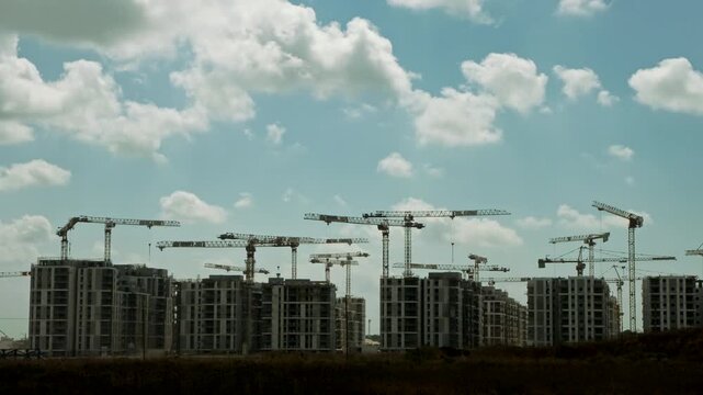 Timelapse of massive residential block construction featuring active tower cranes under cloudy sky
