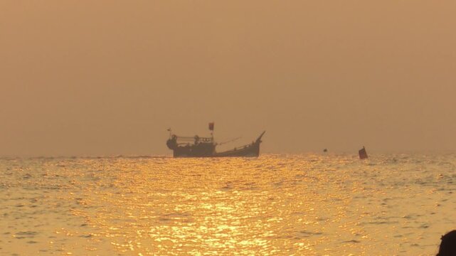 Cinematic shot of a fishing trawler in the middle of the ocean during a breathtaking golden sunrise
