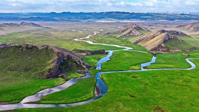 Spectacular aerial footage of a serpentine river winding through lush green meadows in Bayinbuluke Grassland, Xinjiang, China