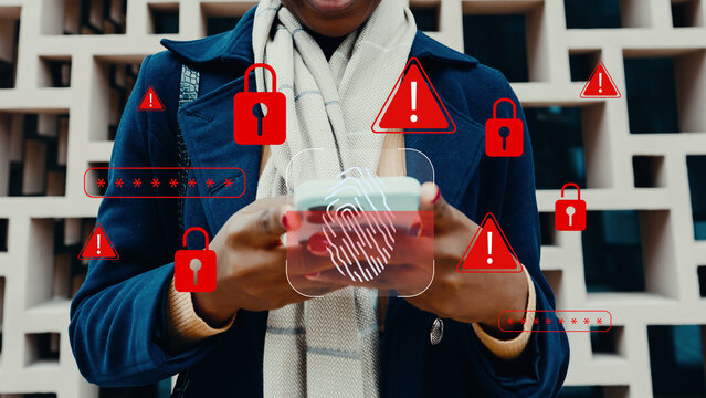Person uses smartphone with security symbols around in a modern urban area during daytime