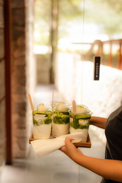 Waiter serving a matcha drinks on wooden tray in cafe.
