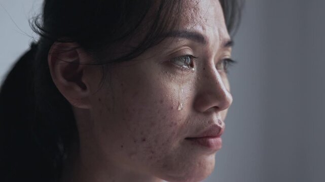 Tearful woman&rsquo;s face in soft light, symbolizing trauma awareness, women&rsquo;s safety, emotional support, healing, and hope.