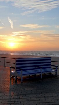 Empty Striped Bench on a Beach Promenade Overlooking a Beautiful Sunset