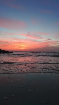 Serene Beach Sunset with Pink and Orange Sky and Gentle Ocean Waves. Vertical Video.
