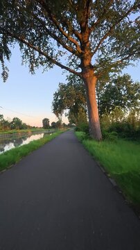 POV shot cycling on a scenic path next to a canal during a beautiful golden hour sunset.