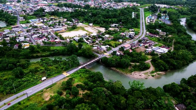 Drone View of River Bridge and Urban Edge in Tropical Ecuador, Green Forest, Roads, Buildings and South American Town Infrastructure Landscape