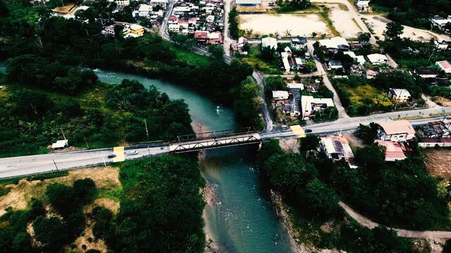 Aerial View of Bridge Over Green River in Ecuador Town, Urban Buildings, Roads, Forest Edge and Tropical South American Travel Landscape