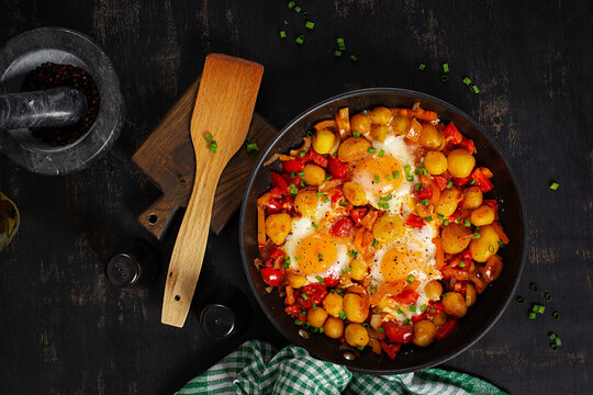 Fried Eggs with Baby Potatoes and Bell Pepper Skillet on Dark Background. Shakshuka Style Eggs. Top view