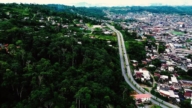 Drone View of Tropical Ecuador Town and Highway Through Green Rainforest Valley, Urban Buildings, Dense Forest and Mountain Travel Landscape