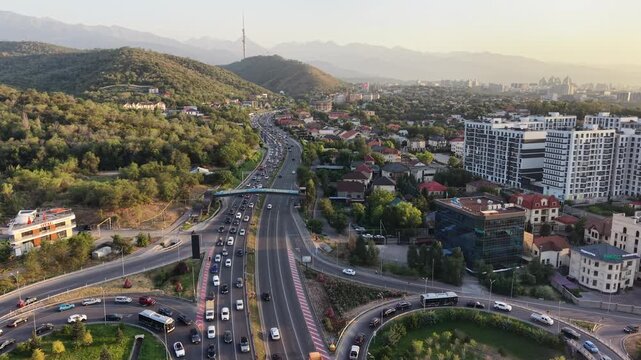 Aerial flyover above city street with scenic view of mountains and Kok Tobe hill at sunset