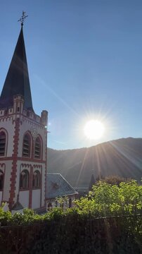 Bacharach, Germany, August 11, 2026 selective focus on historic church surrounded by mountains at sunrise