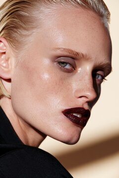 Blonde model with dark lipstick stares softly at camera