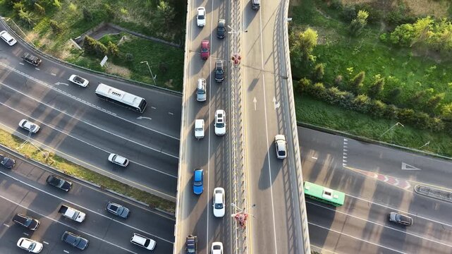 Aerial tracking shot above moving traffic stream on city freeway and overpass