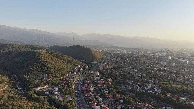 Aerial flyover above city street with scenic view of mountains and Kok Tobe hill at sunset