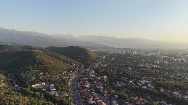 Aerial flyover above city street with scenic view of mountains and Kok Tobe hill at sunset