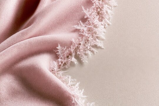 Soft pink fabric with frayed edges lies on a smooth surface