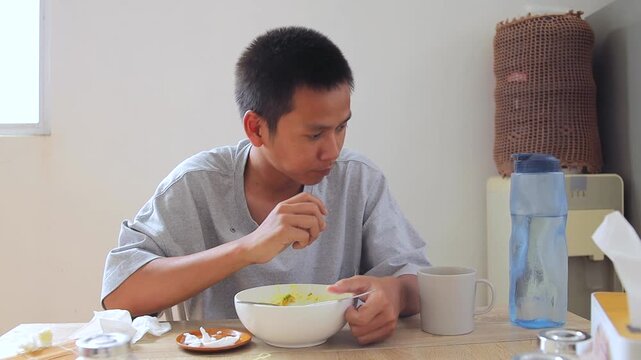 Young asian man choking while eating soto at dining table