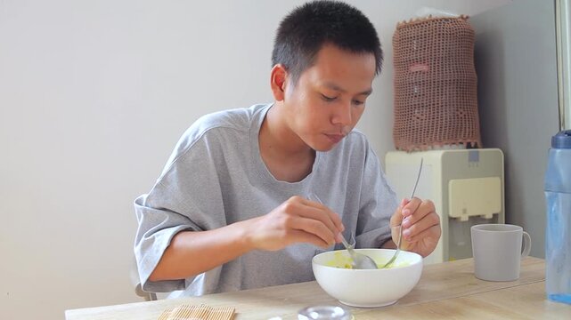 Young asian man Slurping broth and vermicelli in soto at dining table
