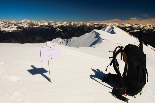 Orobie Alps in winter: a backpack next to the sign marking the summit of Monte Araralta at 2,003 meters above sea level.  Lombardy, Italy, Europe