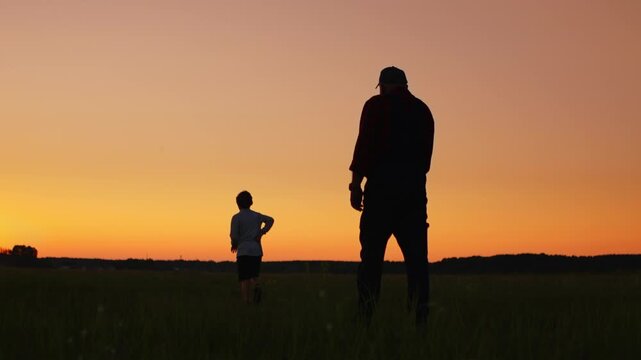 Silhouetted child running toward elder in open field at sunset, capturing playful generational bond, freedom, and peaceful moments in warm golden twilight