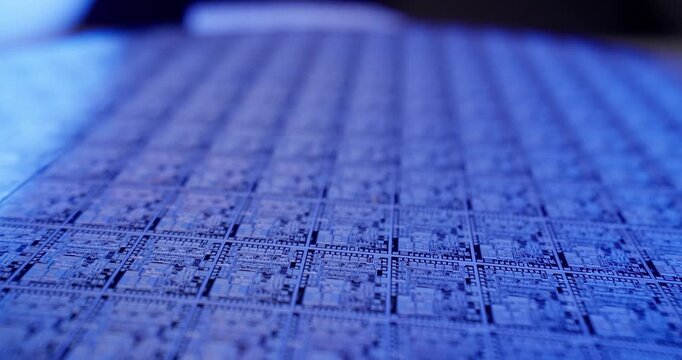 Slow motion closeup of semiconductor wafer grid sliding across production table in cleanroom with shallow depth of field tracking shot, probe view.