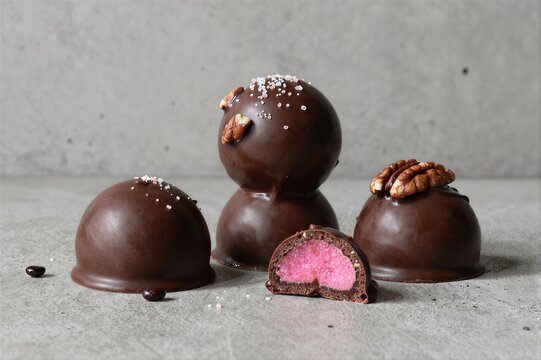 Chocolate truffles with pink filling arranged on concrete