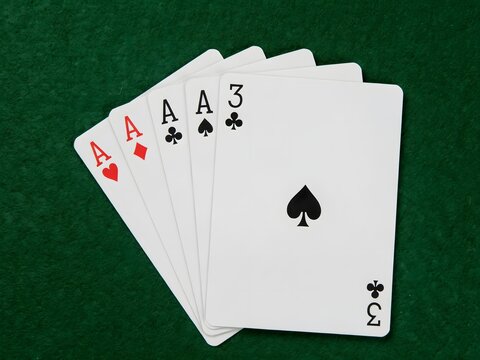 Playing cards featuring ace and three of spades and hearts displayed on green felt table