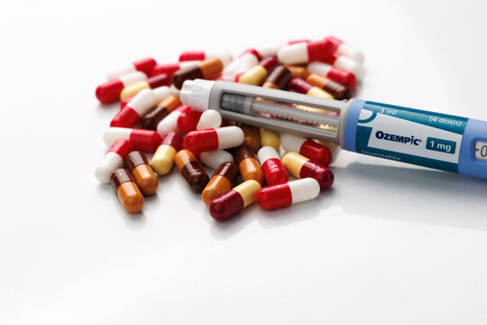 Ozempic Semaglutide GLP-1 injection pen on top of multicolored pills for type 2 diabetes management and clinical obesity weight loss treatment on a white background. In Barcelona -Spain; September 10,