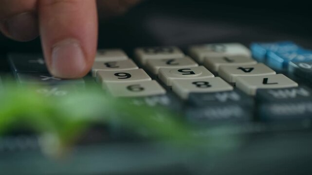 Close up businessman finger pressing buttons on electronic calculator for financial data analysis. Essential accounting equipment for managing business expenses, budget, and profit