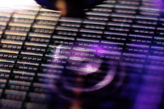 Silicon microchip wafer closeup with purple neon lighting for technology background and semiconductor