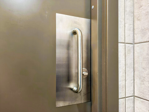 Commercial door push pull plate handle made of stainless steel. Heavy duty industrial entry hardware for office building and restroom. Modern metallic metal door pull mechanism