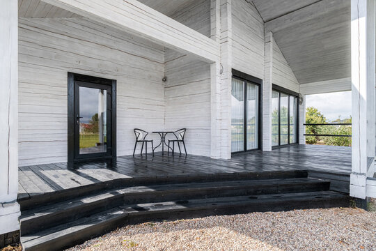 Black wooden deck of white log cabin house