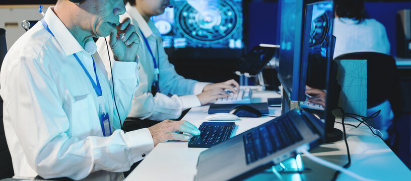 Senior operator with headset analyzing flight radar on monitor in a dark command center. Professional air traffic control or cybersecurity operations concept.
