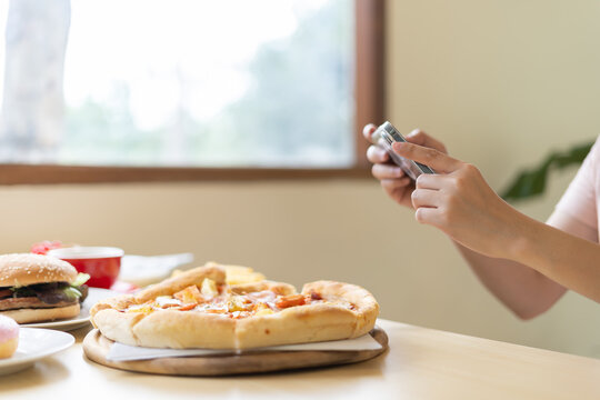 Traveler takes a photo of the food on the table with a smartphone to post on a website. Online food delivery, ordering service, influencer, review, social media, share, marketing, interest.