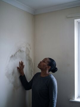 Tenant examining a damp patch on her bedroom wall