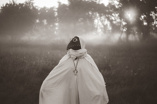 Mysterious masked woman standing alone in autumn Halloween landscape.