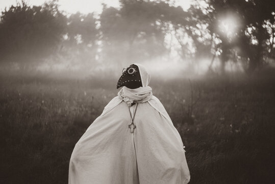 Mysterious masked woman standing alone in autumn Halloween landscape.