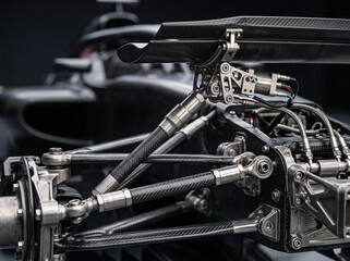 Obraz premium close up view of the intricate rear suspension assembly and defocused wing of a formula 1 race car constructed from carbon and titanium