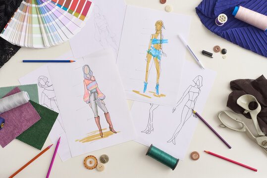 Fashion design sketches lie across paper with fabric swatches, buttons, and pencils. Fashion concept layout presents outfit ideas, color choices, and sewing materials in neat creative workspace.