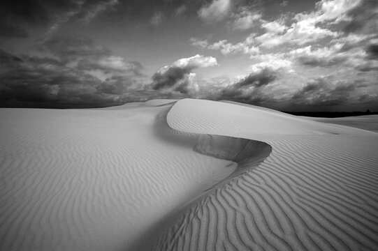 sand dunes in the desert  with a moody cloudy sky in black and white