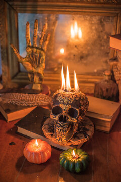 Maya carved skull candle with burning flames on old spell book, pagan ritual altar and esoteric concept 