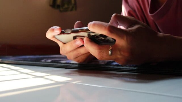 A person plays a mobile game on a smartphone holding the device horizontally with both hands