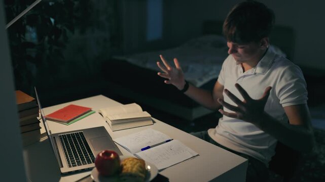 Stressed teen youth covering his face failing a difficult late night homework.