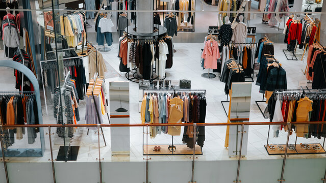 A clothing store features multiple displays of various apparel for sale. Racks hold a variety of garments, including shirts, dresses, and outerwear, arranged in an organized manner